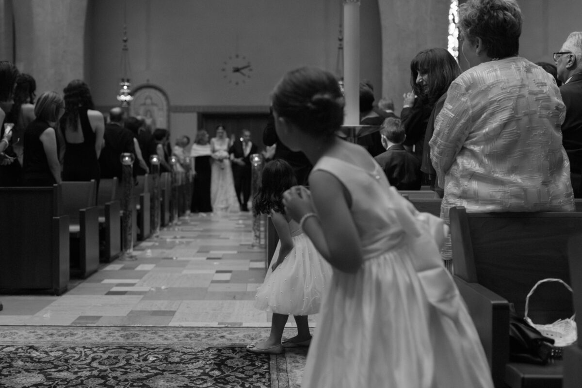Flower girl watching the bride come down the aisle of the church.