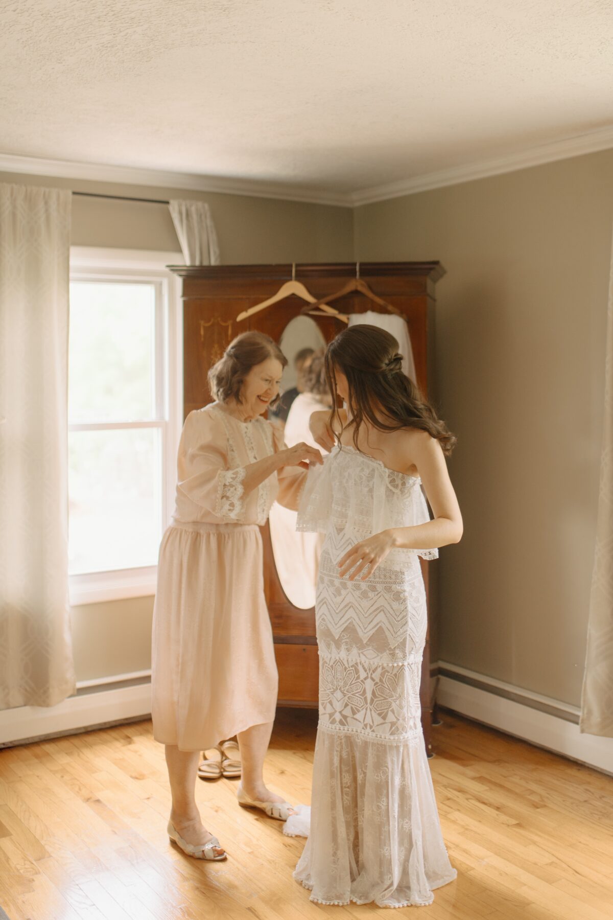 Mother of the bride helping her daughter into her wedding dress.