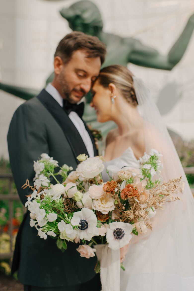 A couple posing in front of the spirit of Detroit on their wedding day