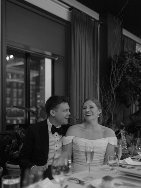 A bride and groom laughing during speeches at their Book Tower Wedding.