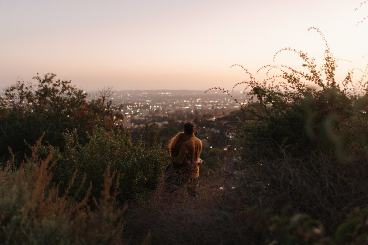 A couple overlooking Los Angeles at night from a hilltop
