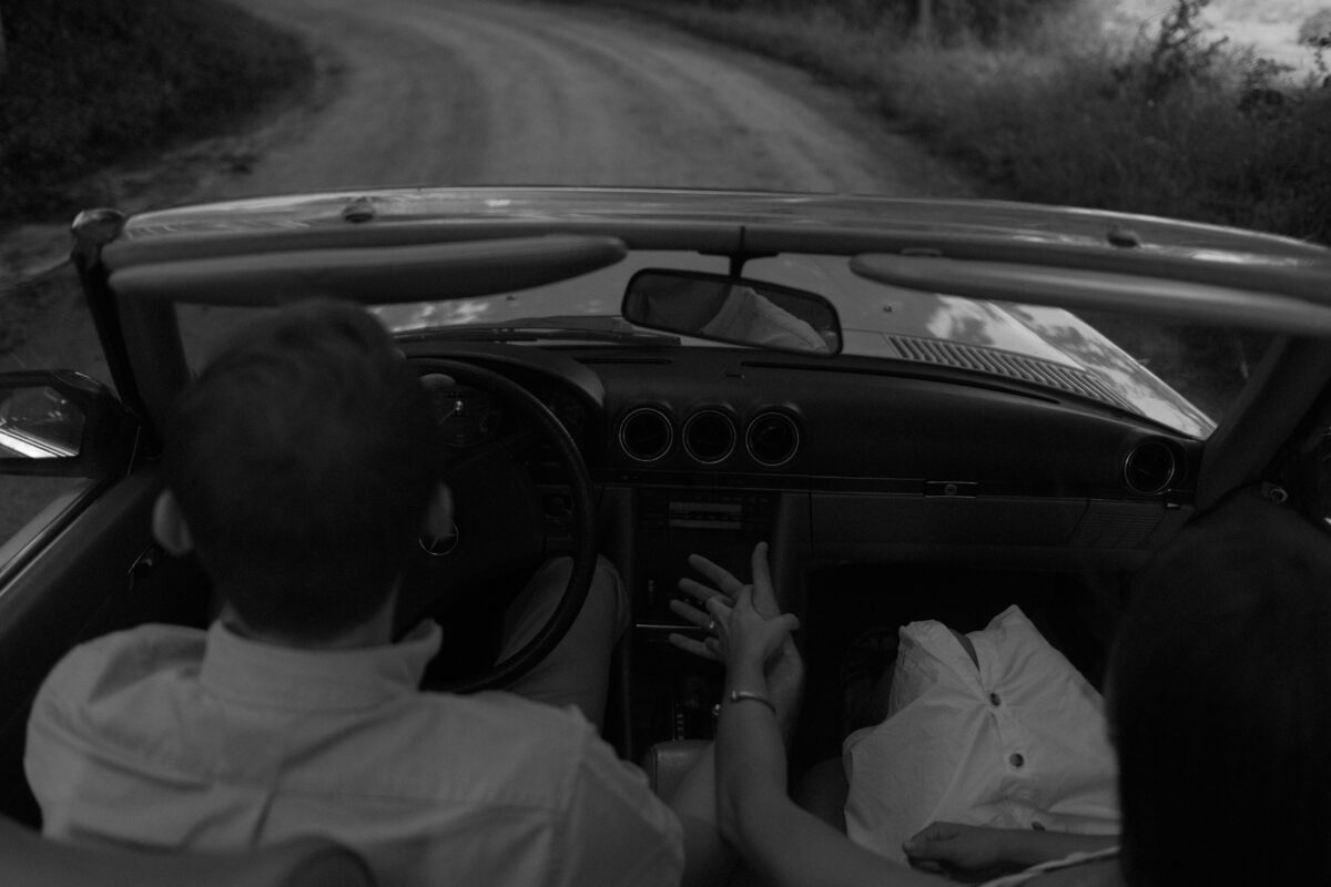 Couple riding down a country road in a classic car during their engagement session.
